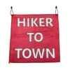 Red fabric banner with bold white letters reading 'HIKER TO TOWN,' hung by two black cords on either side.